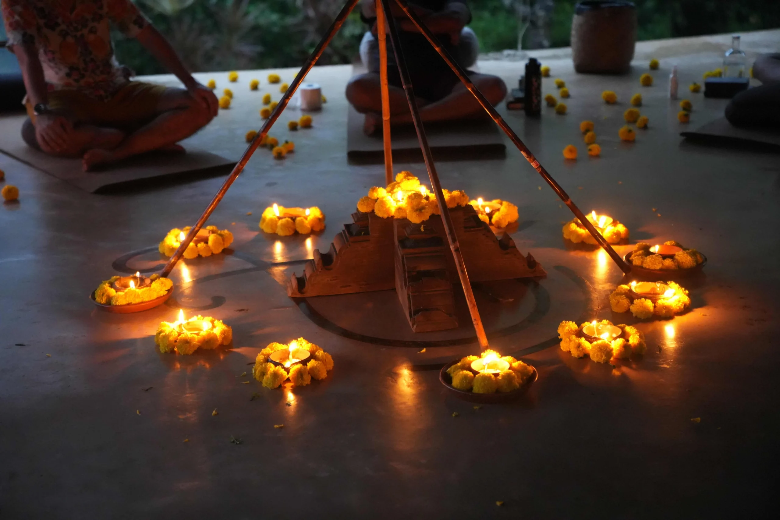 Candlelit ritual setup with flowers and central structure, creating a grounded, meditative space.